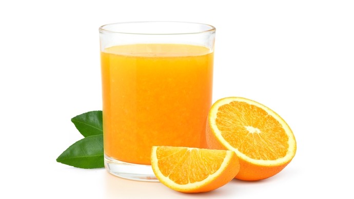 a glass of orange juice next to an orange cut in half