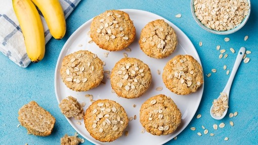 Perfectly baked golden banana and honey muffins pictured next to a bunch of whole bananas
