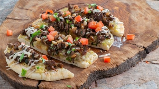 a crispy flatbread topped with lamb mince, chopped tomatoes and cheese