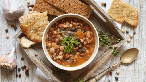 A bowl of mixed lentils and beans with served with two crispy breads