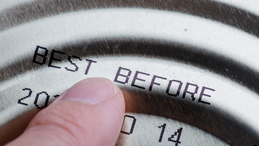 Finger pointing at the top of a can of food showing a best before date