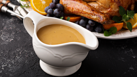 Thick smooth gravy in a white gravy boat ready to be served