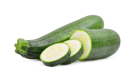 A whole courgette next to slices of courgette