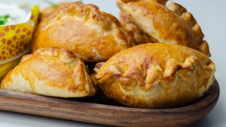 Four golden pastry covered pasties on a serving plate