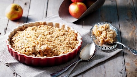 a dish of apple crumble with a portion on a spoon