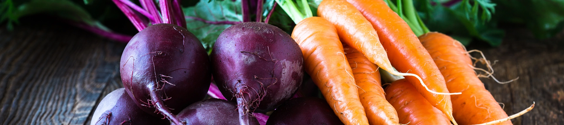 Beetroots and carrots with tops laid out on a table