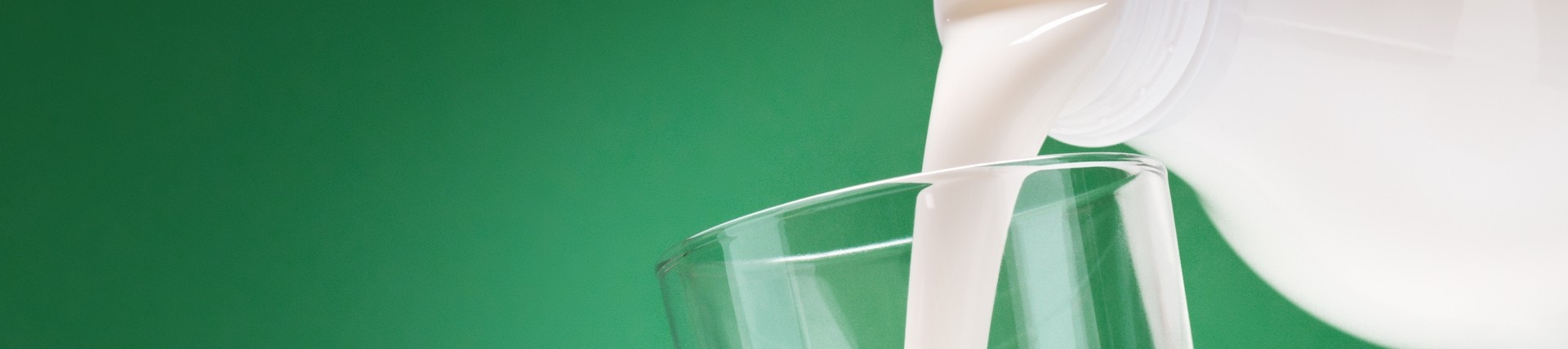 Milk being poured into a glass on a green background